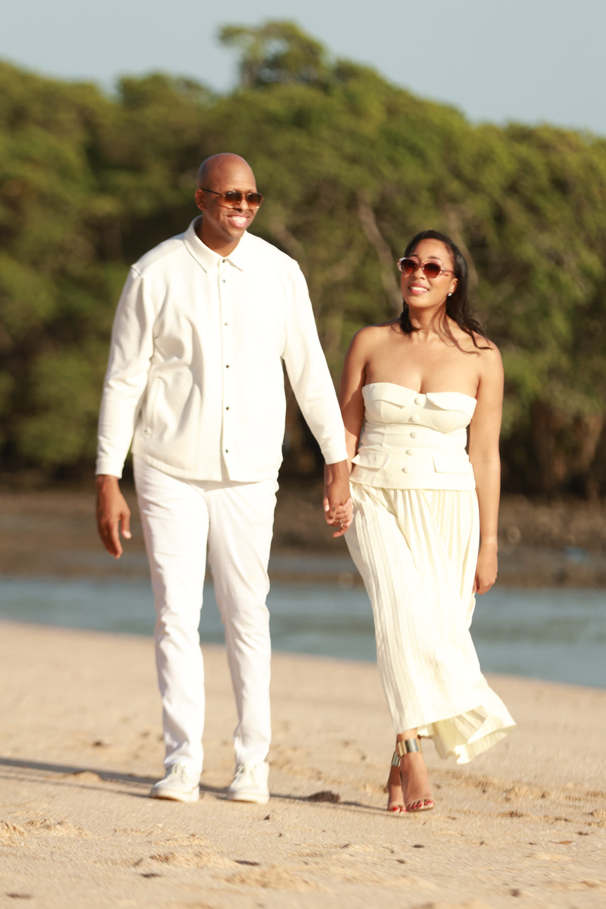 Breanna and Rob walking hand in hand on a beach