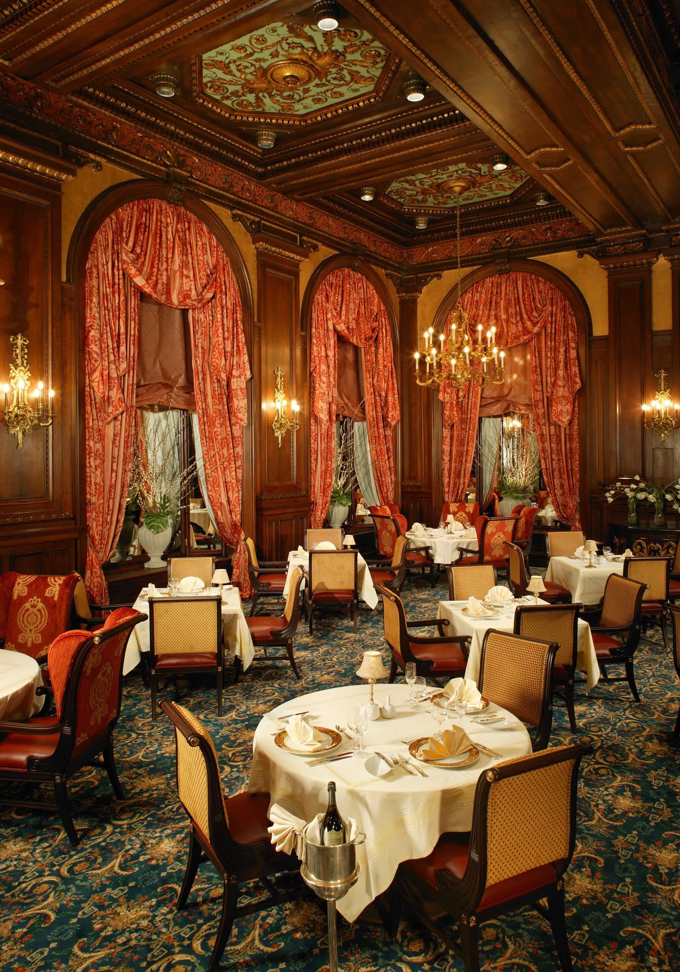 The gilded Green Room at Hotel DuPont, with chandeliers, carved wood, and set tables
