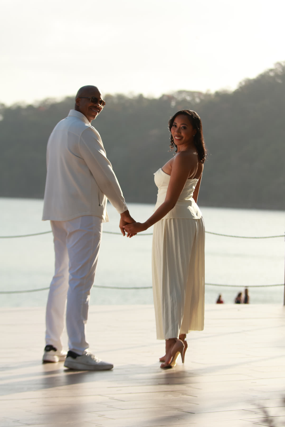 Breanna and Rob holding hands by the water, looking back